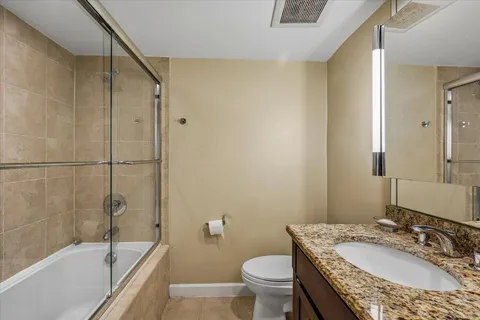 a bathroom with a granite countertop sink a toilet and shower