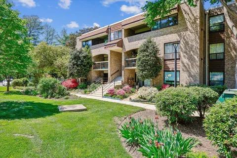 a front view of a multi story residential apartment building with yard and green space
