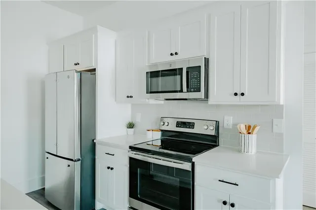 a kitchen with stainless steel appliances a stove a microwave and a white cabinets