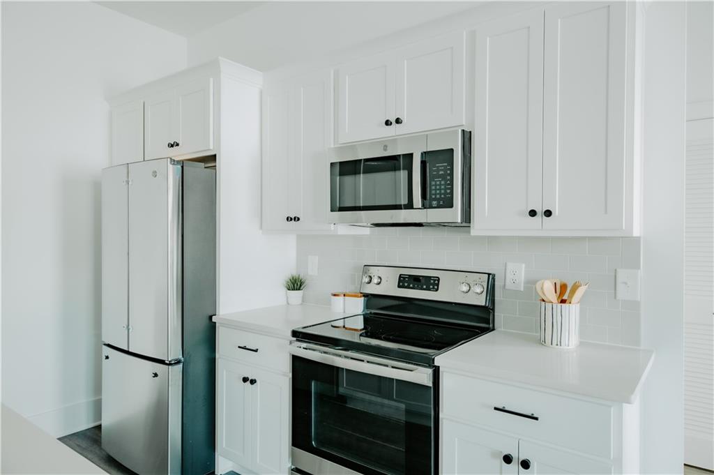 117 Mayson Avenue Northeast, Unit C Atlanta, GA 30307 - Photo 6 of 30 a kitchen with stainless steel appliances a stove a microwave and a white cabinets