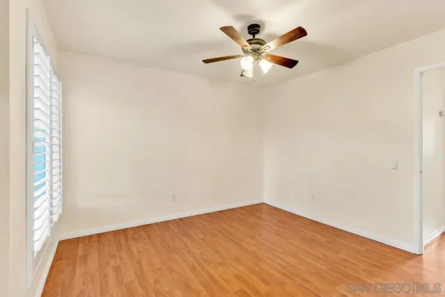 an empty room with a chandelier fan and wooden floor