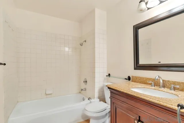 a bathroom with a granite countertop sink a toilet and a bathtub