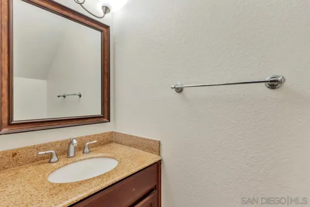 a bathroom with a granite countertop sink and a mirror