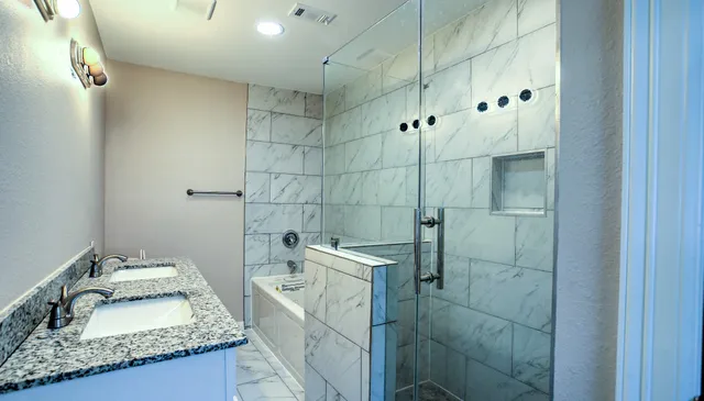 a bathroom with a granite countertop sink a toilet and shower