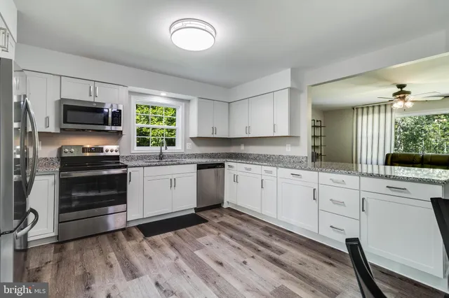 a kitchen with granite countertop a refrigerator stove and microwave