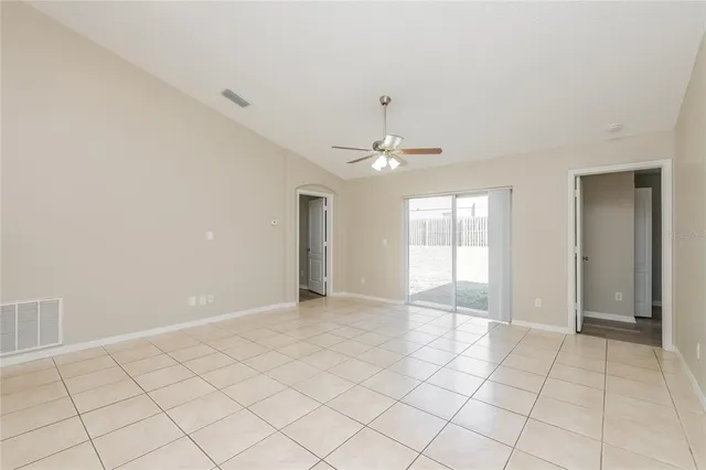 a view of an empty room with window and chandelier fan