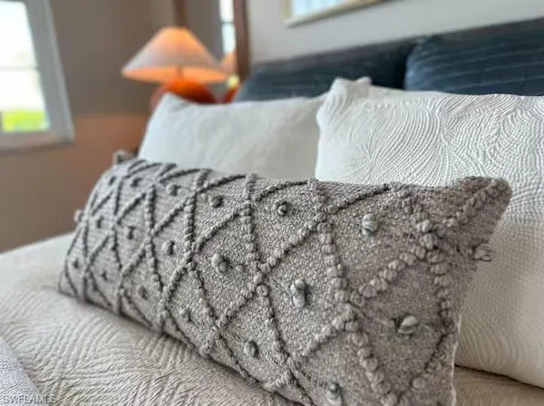 a bed with a white comforter and pillows