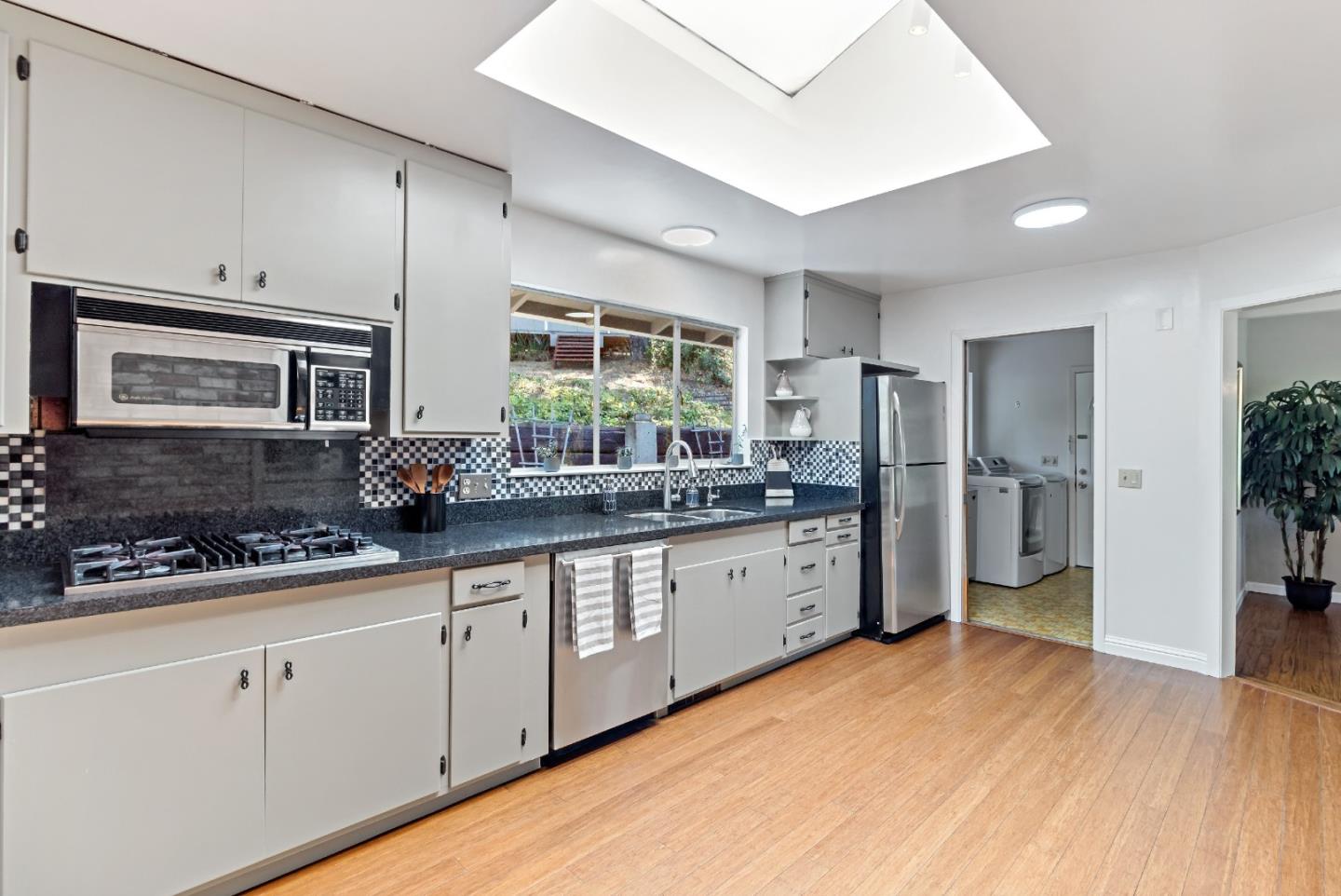 335 Harcross Road Woodside, CA 94062 - Photo 22 of 72 a kitchen with granite countertop a refrigerator and wooden cabinets