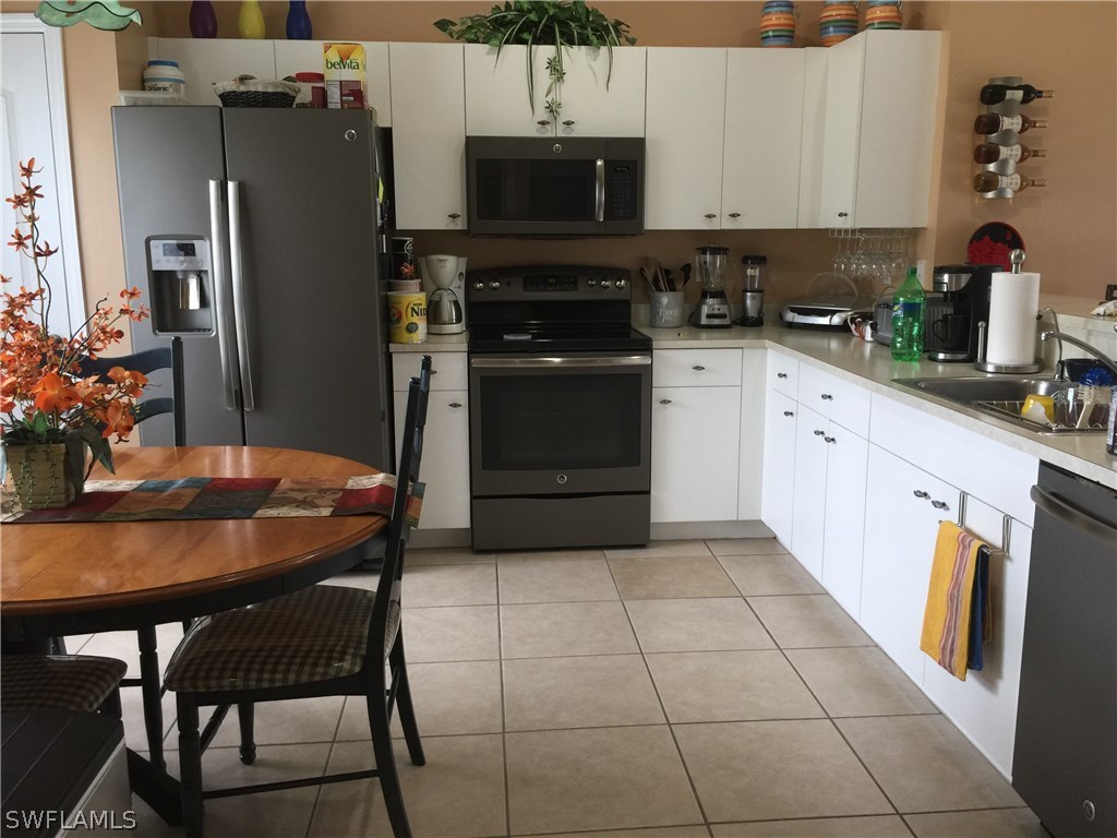 3115 Meadow Road Lehigh Acres, FL 33974 - Photo 4 of 23 a kitchen with stainless steel appliances a stove a refrigerator and a dining table