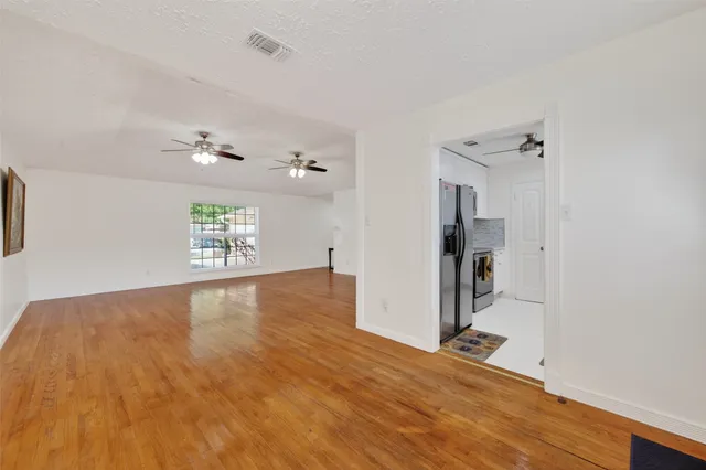 a view of an empty room with a window and wooden floor