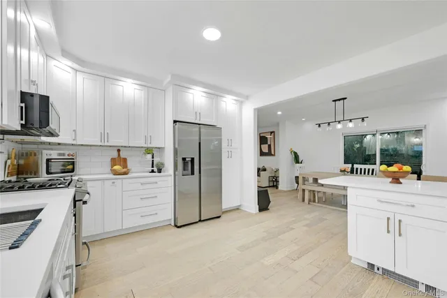 a large white kitchen with a large window and stainless steel appliances