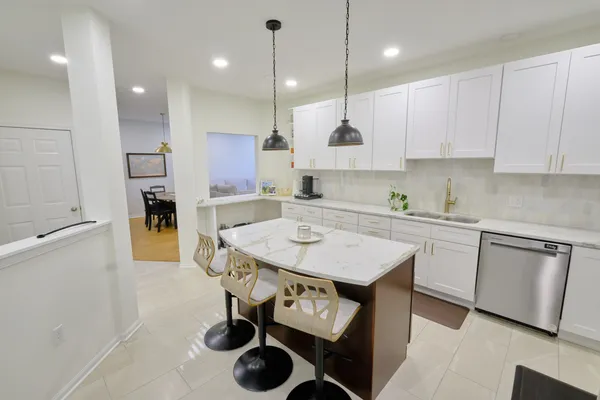 a kitchen with a sink a refrigerator and white cabinets