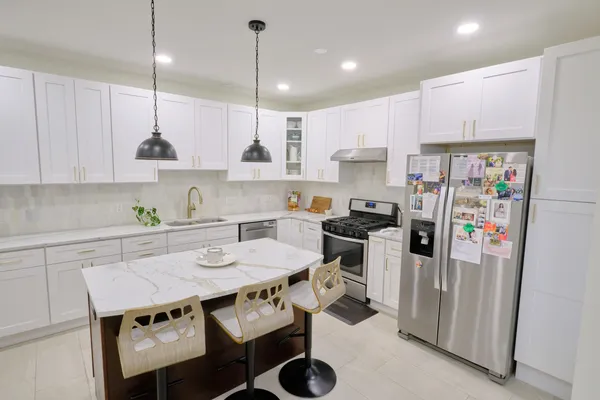 a kitchen with stainless steel appliances granite countertop a sink a stove a refrigerator and chairs with wooden floor