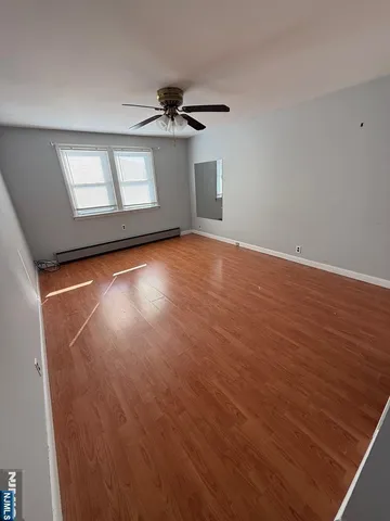 a view of empty room with wooden floor and fan