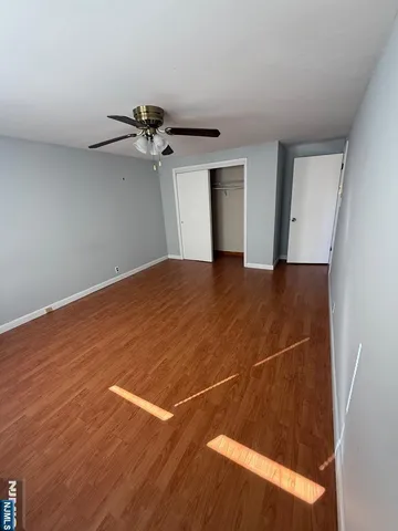 a view of a room with a ceiling fan and wooden floor