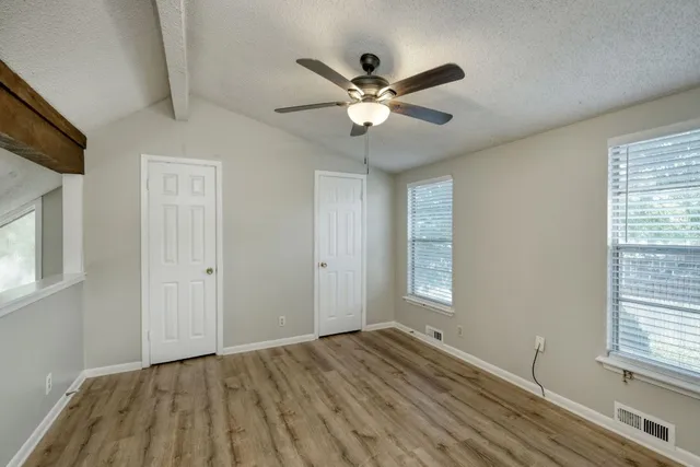 a view of empty room with wooden floor and fan