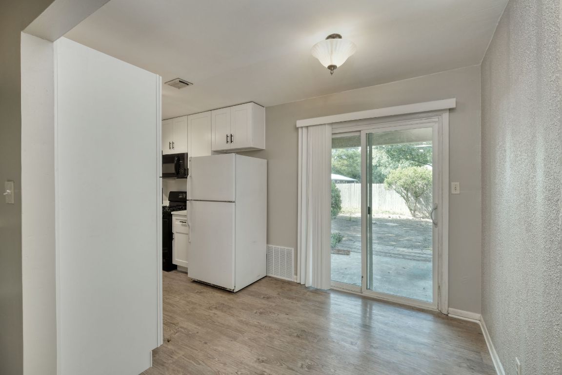 2711 St Edwards Circle, Unit 2 Austin, TX 78704 - Photo 6 of 17 Kitchen with white cabinets, black appliances, light wood finished floors, and a textured wall