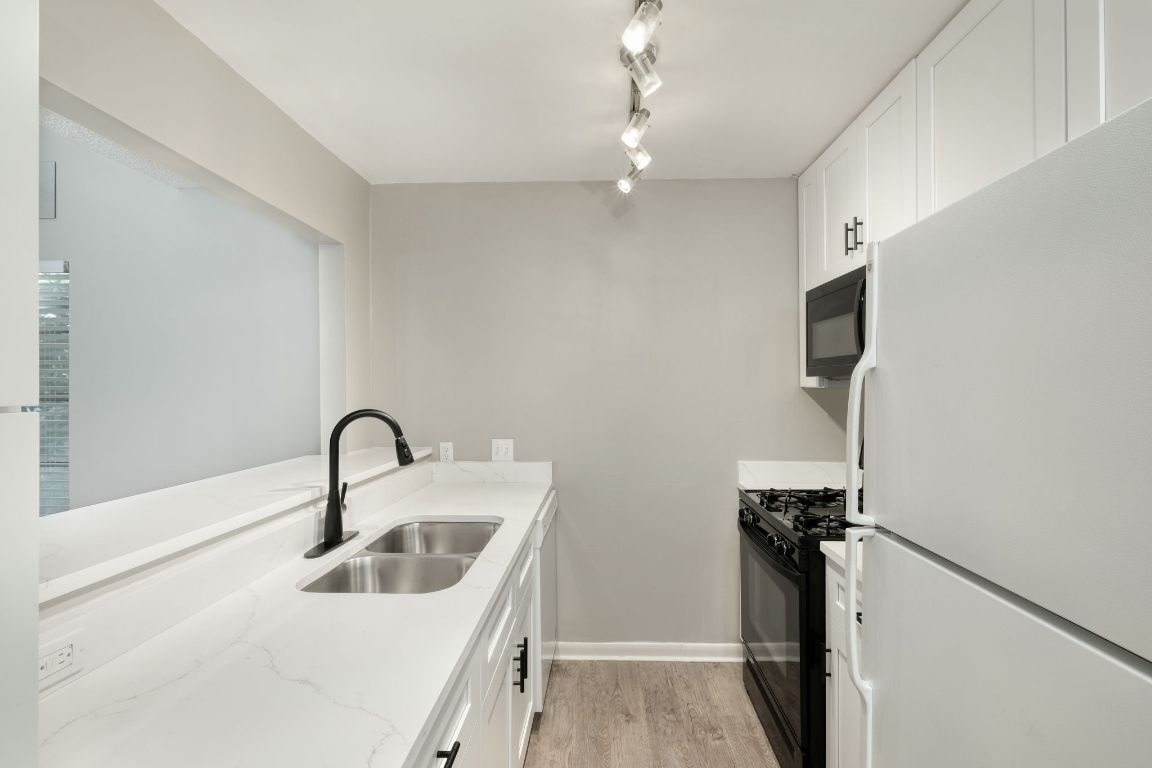 2711 St Edwards Circle, Unit 2 Austin, TX 78704 - Photo 7 of 17 Kitchen featuring black appliances, white cabinets, light wood finished floors, and light stone counters