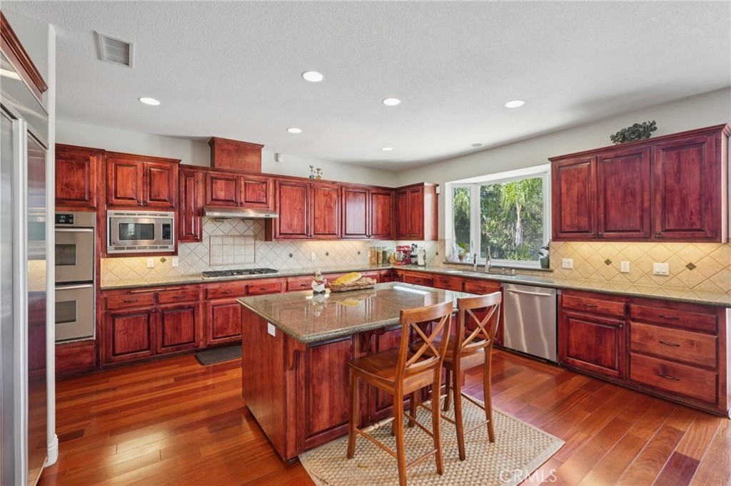 30810 Avenida Del Reposo Temecula, CA 92591 - Photo 10 of 75 a kitchen with stainless steel appliances granite countertop wooden cabinets a center island and a window