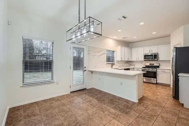 a kitchen with a refrigerator a sink and white cabinets