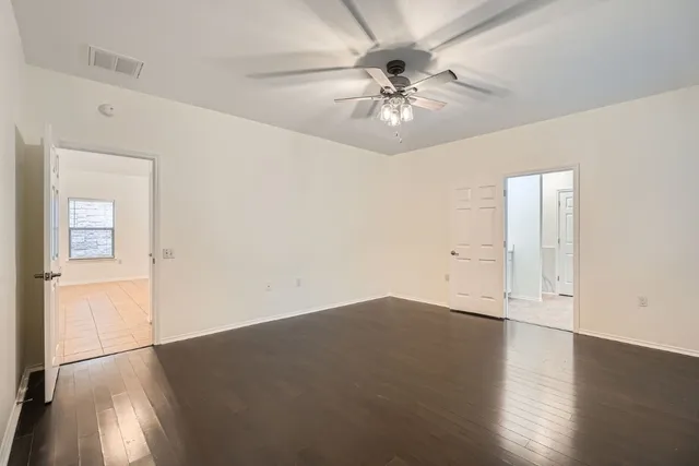 an empty room with wooden floor closet and fan