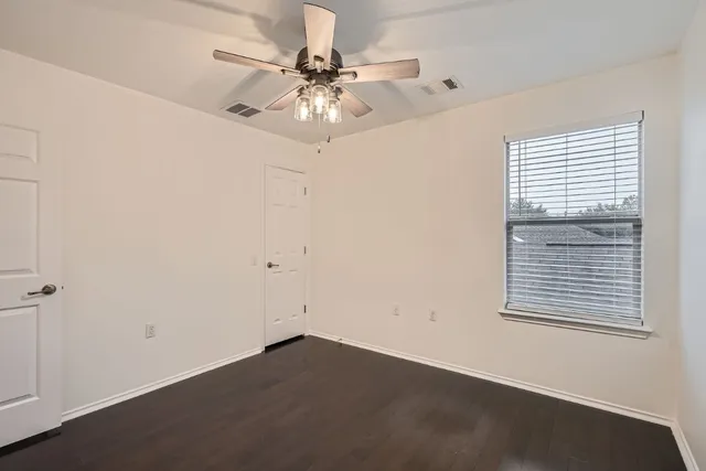 an empty room with a window and a fan