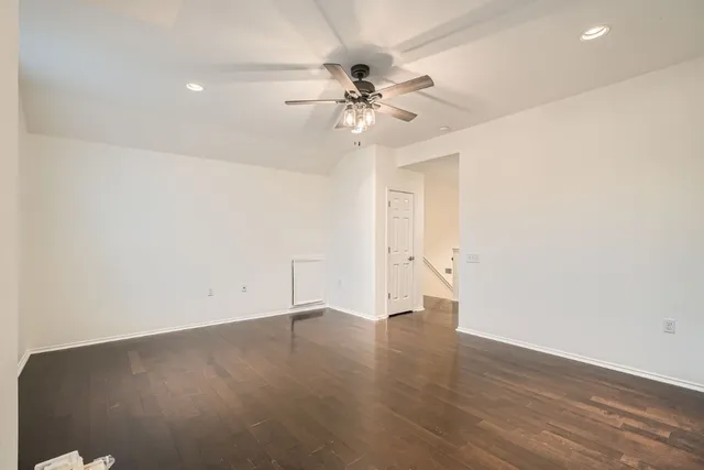 an empty room with wooden floor and fan