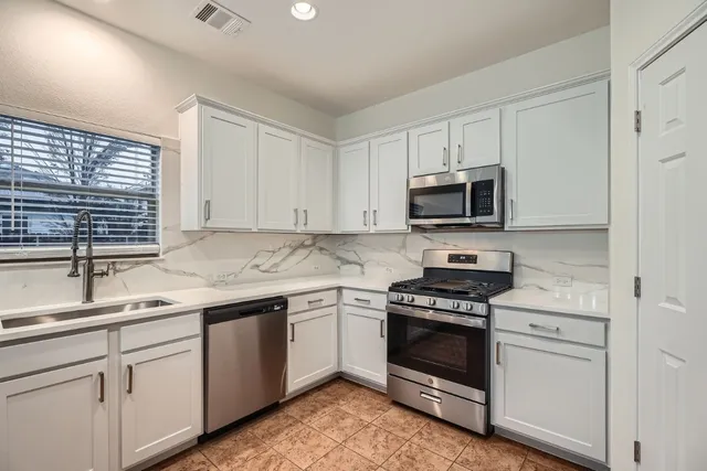 a kitchen with cabinets stainless steel appliances and a sink