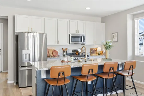 a kitchen with stainless steel appliances granite countertop a dining table chairs refrigerator and sink