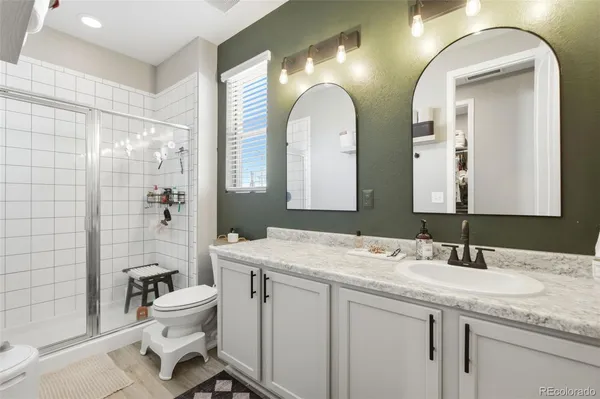 a bathroom with a granite countertop sink a toilet a mirror and shower