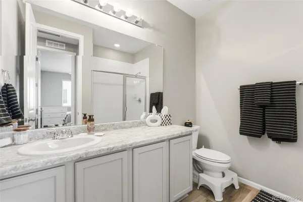 a bathroom with a granite countertop sink toilet and mirror