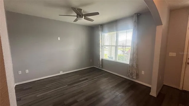 a view of an empty room with a window and wooden floor
