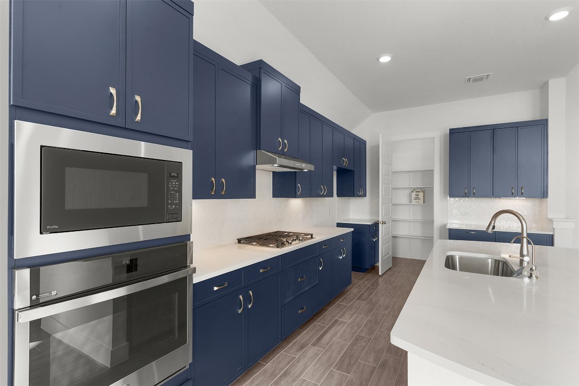 333 Ridgewell Loop Georgetown, TX 78633 - Photo 9 of 29 Kitchen featuring blue cabinetry, stainless steel appliances, wood finish floors, and under cabinet range hood
