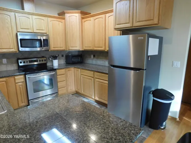 a kitchen with stainless steel appliances granite countertop a refrigerator a stove a sink and cabinets