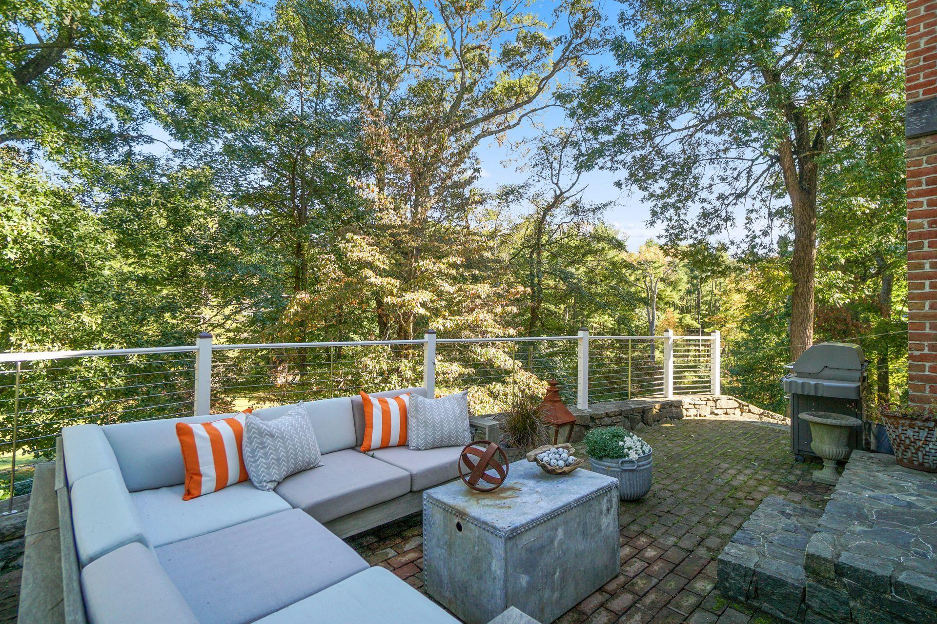 33 Tory Hole Road Darien, CT 06820 - Photo 43 of 51 a view of a patio with couches chairs and a fire pit with large trees