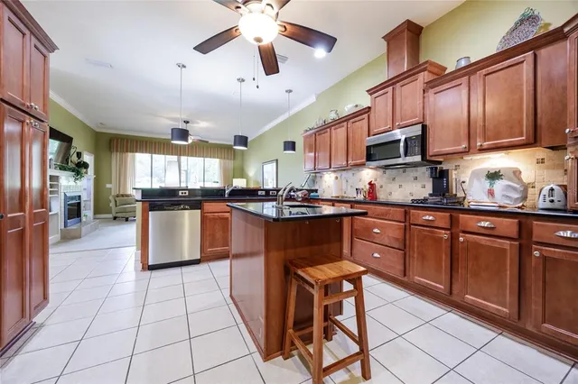 a kitchen with stainless steel appliances granite countertop a stove top oven a sink a dining table and chairs