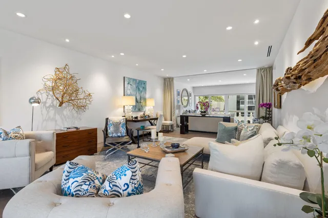 a living room with furniture kitchen view and a large window