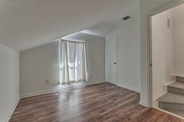 a view of an empty room with window and wooden floor