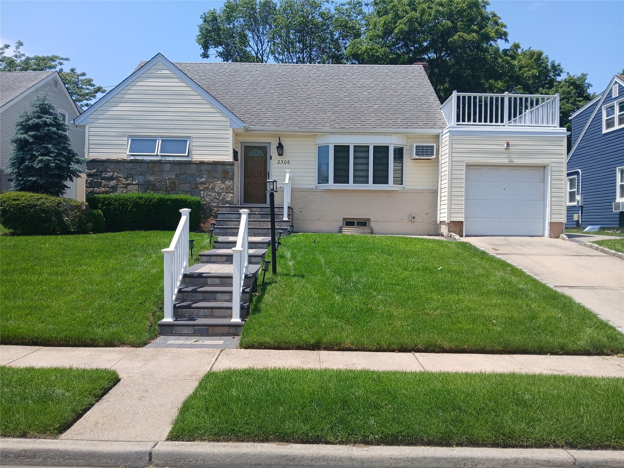 2306 Charing Cross Road Baldwin, NY 11510 - Photo 1 of 1 View of front of house featuring a front lawn, concrete driveway, an attached garage, and a balcony