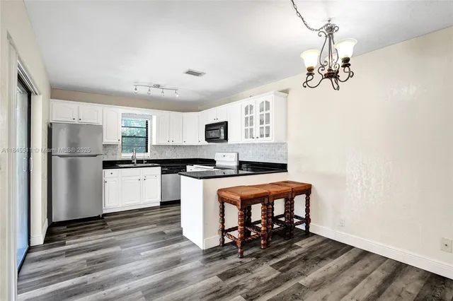 a large kitchen with stainless steel appliances granite countertop a refrigerator and a stove top oven