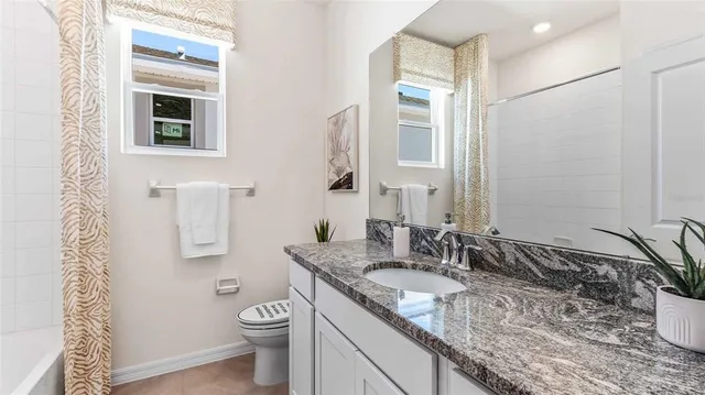 a bathroom with a granite countertop sink toilet and mirror
