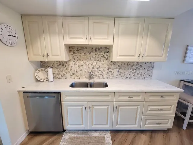 a kitchen with white cabinets and sink