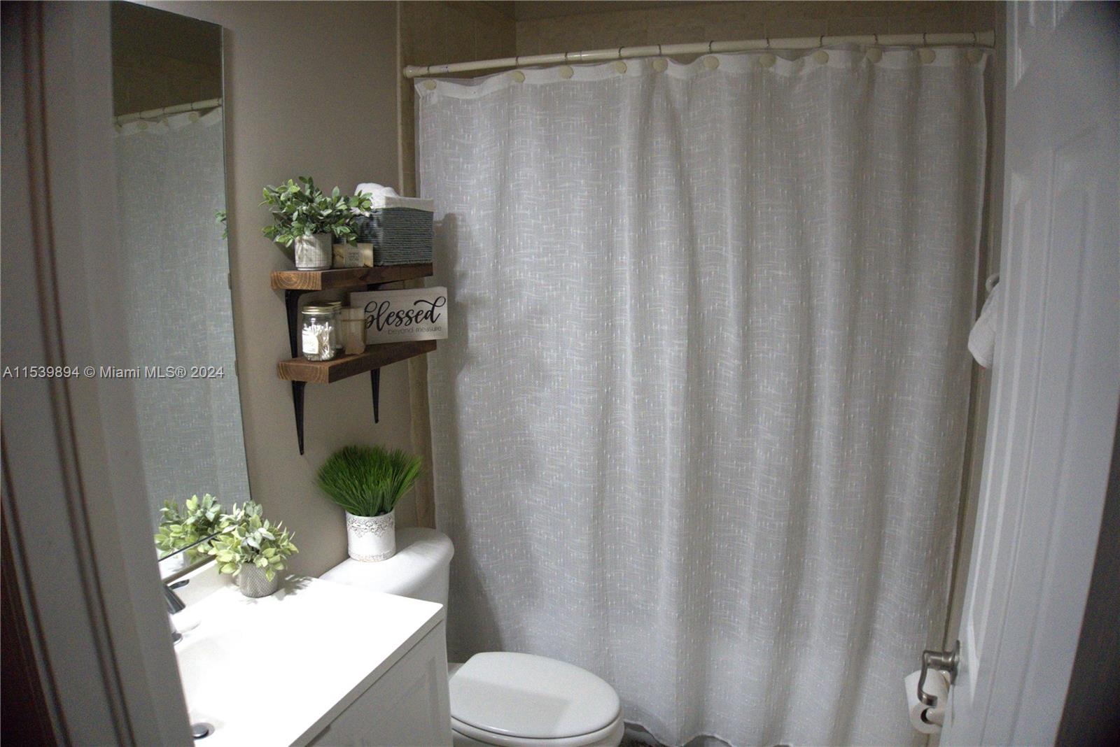 9143 Southwest 227th Street, Unit 3 Cutler Bay, FL 33190 - Photo 25 of 35 a bathroom with a toilet and a shower curtain