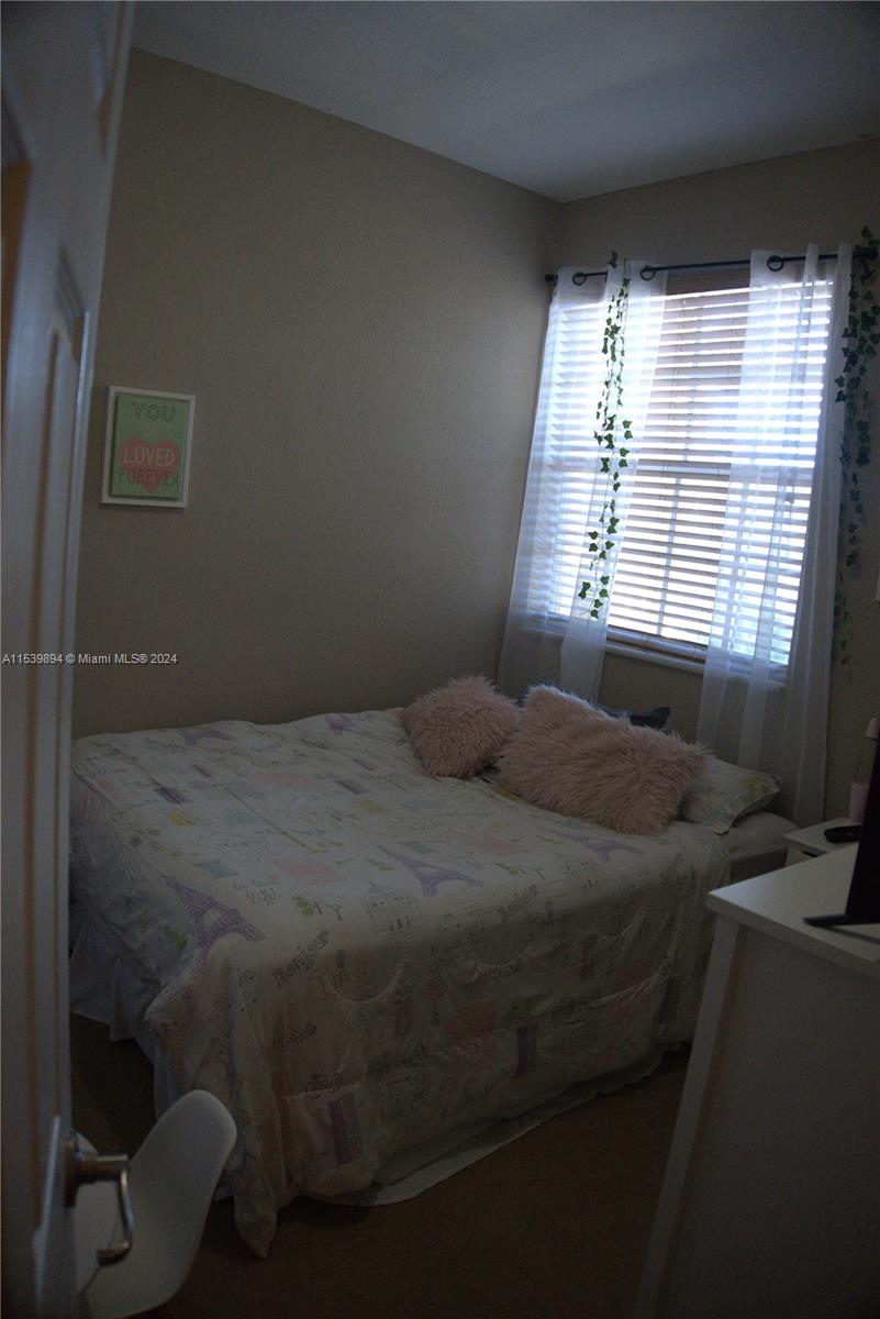 9143 Southwest 227th Street, Unit 3 Cutler Bay, FL 33190 - Photo 31 of 35 a bed sitting in a bedroom next to a window