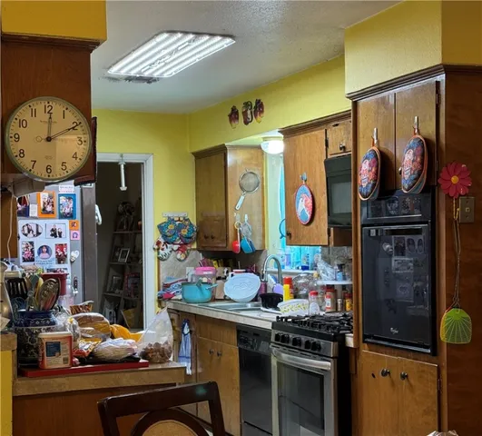 a kitchen area with stainless steel appliances kitchen island granite countertop a stove a refrigerator and a dining table