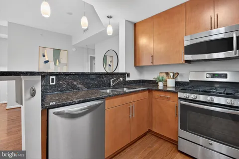 a kitchen with stainless steel appliances granite countertop a stove a sink and a microwave