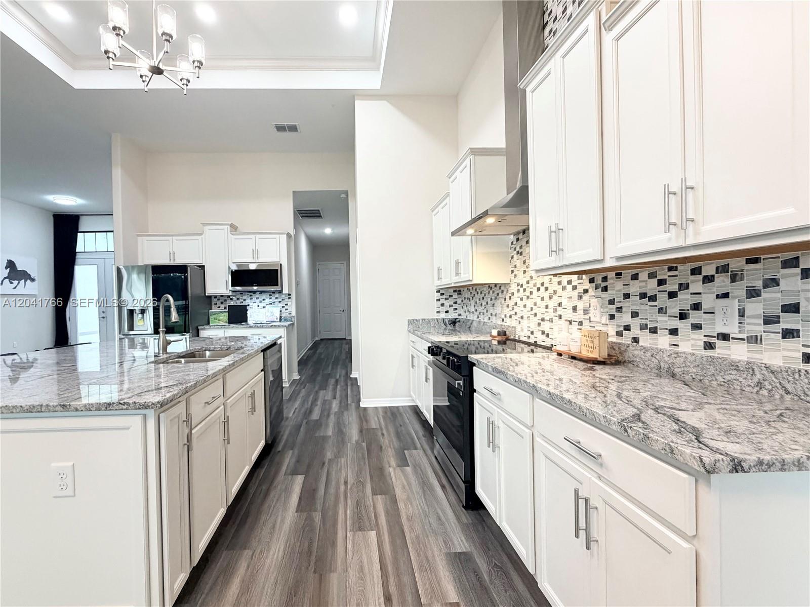 7041 Northeast 22nd Ct Road Ocala, FL 34479 - Photo 25 of 55 a large white kitchen with stainless steel appliances granite countertop a lot of counter space and wooden floors