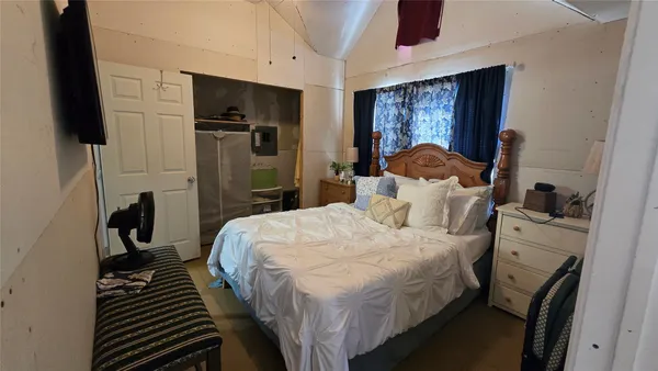 a bedroom with a bed and a flat tv screen on dresser