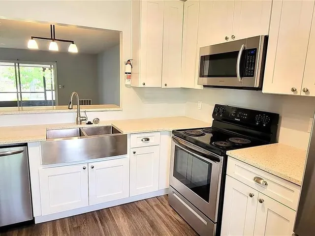 a kitchen with granite countertop a sink stainless steel appliances and cabinets