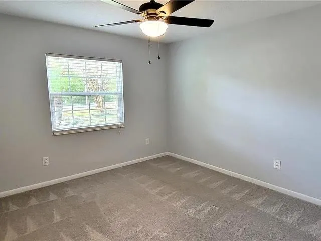 an empty room with a window and a fan
